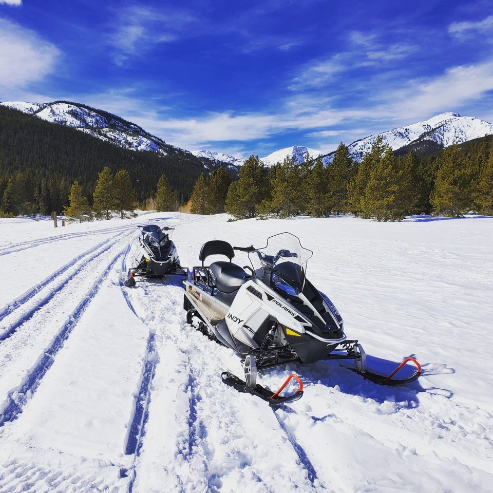 Snowmobiles on a groomed mountain trail